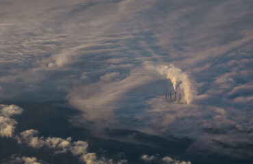 Industrial Emissions – Climate Positive Challenges Aerial view of industrial smokestacks emitting CO2 into the atmosphere – a challenge that Climate Positive strategies aim to solve by removing emissions and restoring balance.
